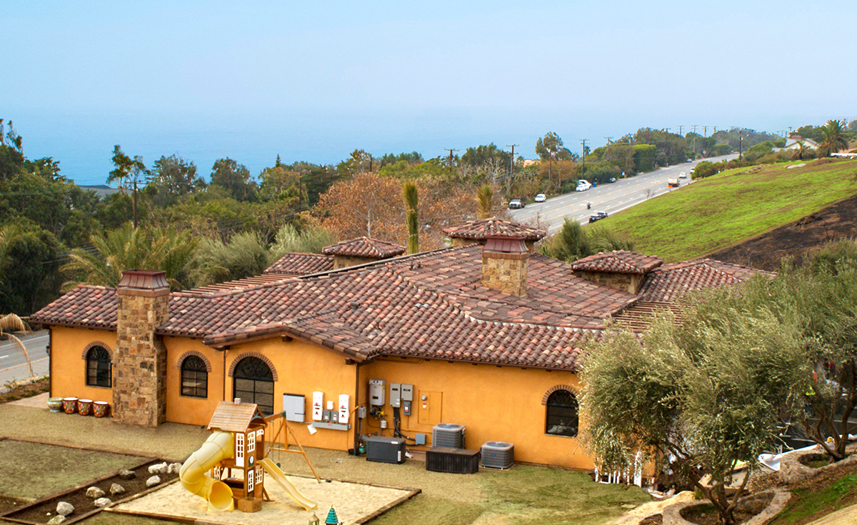Hilltop view of Corona Tapered mission two piece clay roof tile in custom blend 50% 2F45CC16D, 20% B317-R Taupe Smoke Blend, 20% 2F45 Tobacco, 10% B330-R Santa Barbara Blend with 100% 2F45 pans and boosters to match tops on gorgeous one story house in Malibu California