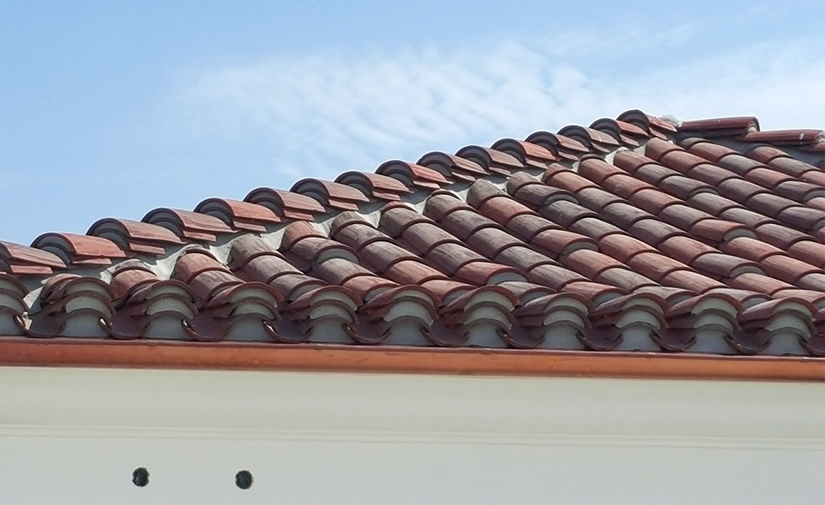close up view of corona tapered mission two piece clay roof tile with mortar and boosting in various custom blends on rooftop of outlets at san clemente california.