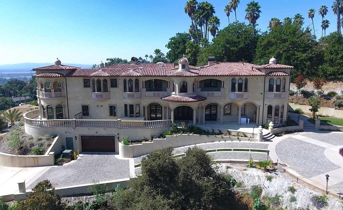 Full front view of custom mansion on a hilltop in Bradbury California featuring Classic Tapered two piece terra-cotta clay roof tile with turrets, domes, and dome awnings in custom color blend CB477.