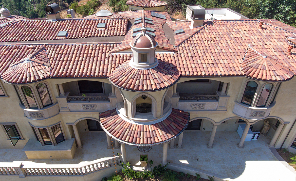 View of front turrets and roof on custom mansion on a hilltop in Bradbury California featuring Classic Tapered two piece terra-cotta clay roof tile with turrets, domes, and dome awnings in custom color blend CB477.